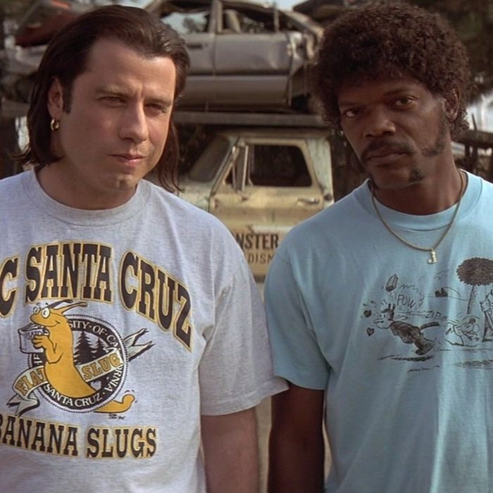 John Travolta and Samuel L. Jackson stand outside, with a tow truck in the background loaded with cars. Travolta is sporting a UC Santa Cruz Banana Slugs T-shirt, while Jackson dons a blue tee.