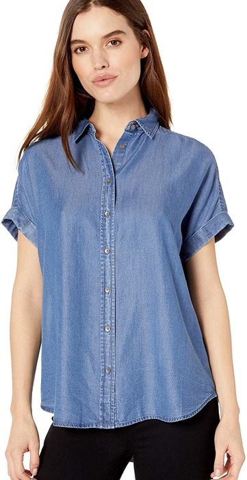 A model is wearing a medium-wash short-sleeve shirt by Daily Rituals.