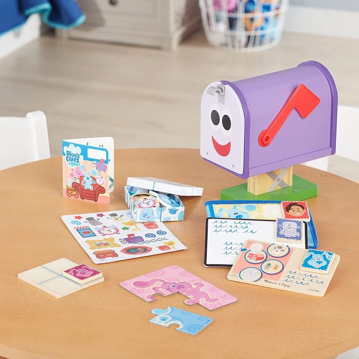 A purple toy mailbox with a face, accompanied by pieces of pretend mail