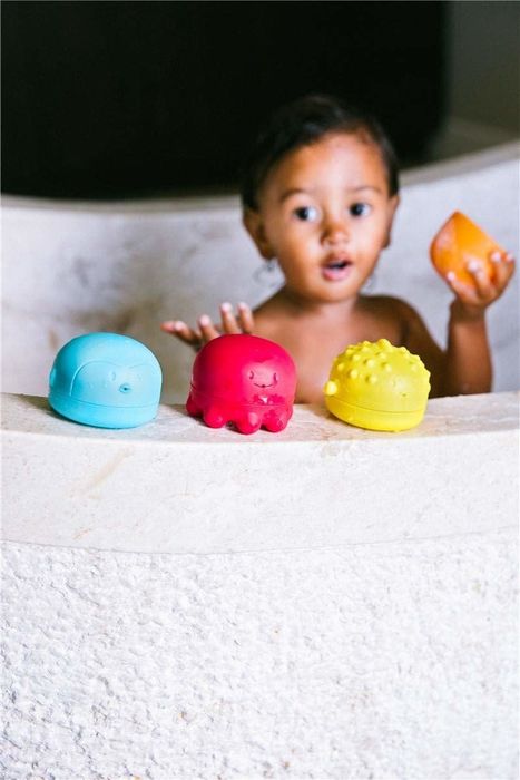 the bath toys lined up on the edge of a bath