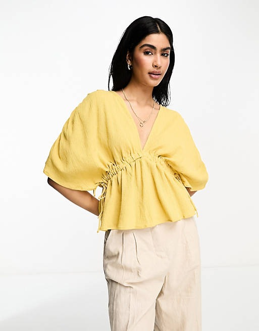 a model wearing the blouse in yellow