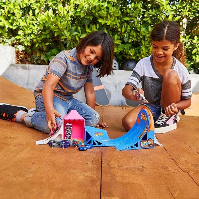 Two children playing with a blue and pink skate ramp