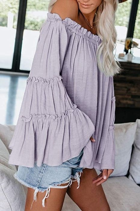 a model wearing the top in light purple, showing off its tiered bell sleeves