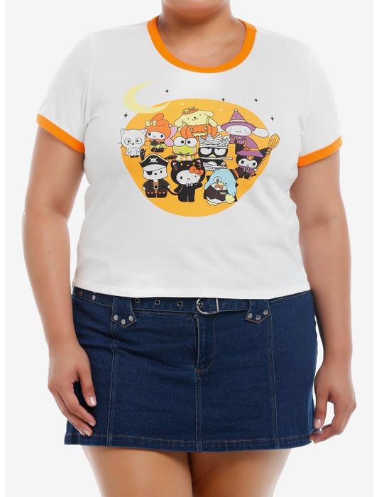 A person wearing a white T-shirt with an orange collar showcasing a cartoon of Hello Kitty and friends in Halloween costumes, paired with a denim skirt