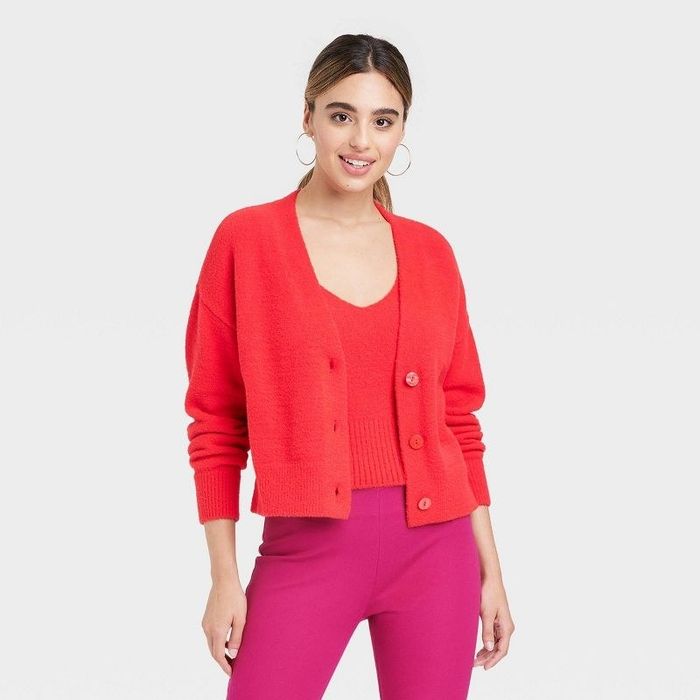 A model in a red cardigan and matching shirt paired with pink pants.