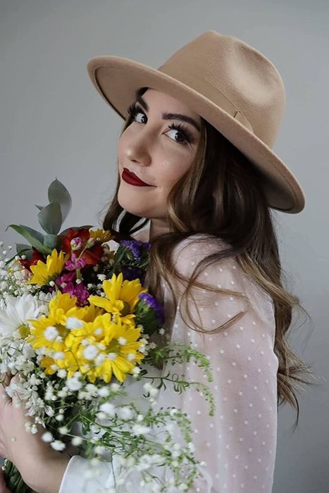 A reviewer holding a bouquet of flowers while wearing a white shirt.