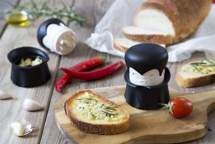 The garlic mincer shaped like Dracula (just twist the head to mince) next to garlic bread.