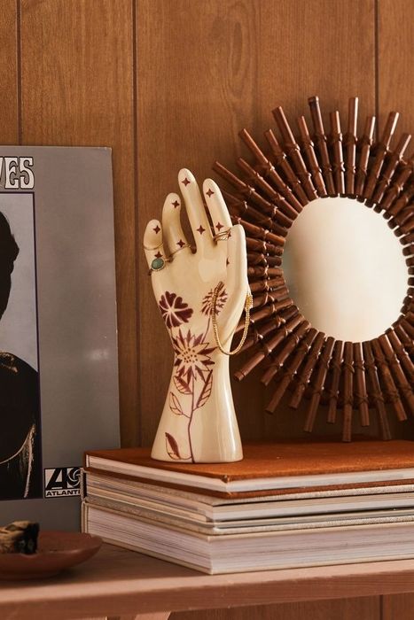 A maroon hand-shaped jewelry holder designed to hold rings, bracelets, or other accessories.