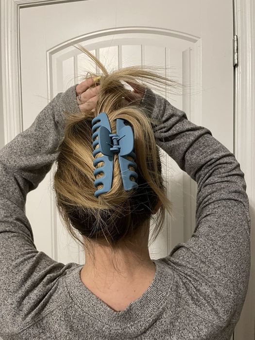 A reviewer's blue claw clip styled in their hair, showcasing its practicality and style.