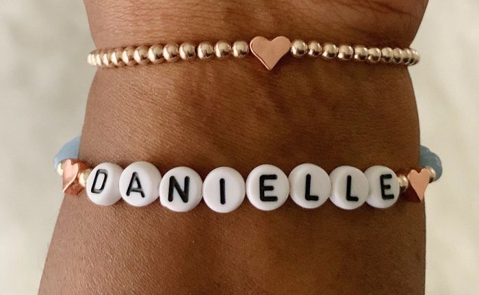 A gold beaded bracelet with rose gold hearts, paired with a personalized beaded name bracelet.
