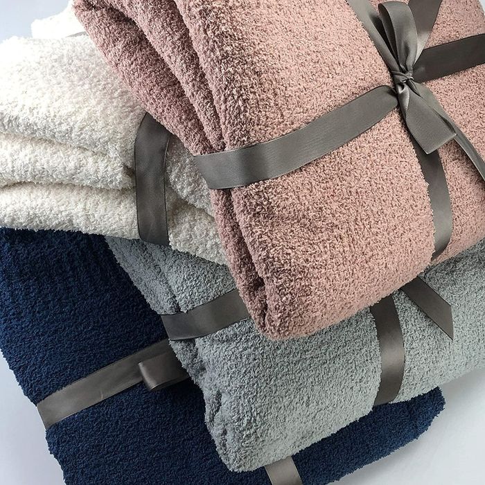 The blanket in dusty rose, blue, ivory, and navy stacked on top of each other
