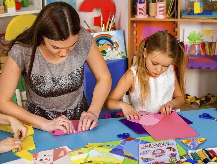 An adult and child model working together on the origami kit.