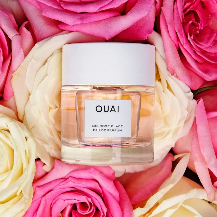 A perfume bottle resting atop a bed of roses.