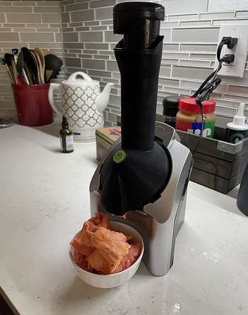 The black Yonanas device on a table with sorbet in a bowl underneath it.