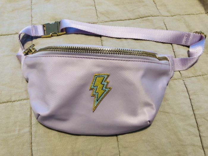 A lavender fanny pack featuring a lightning bolt patch.