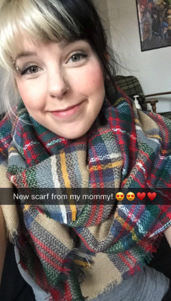A reviewer wearing a plaid scarf in shades of tan, yellow, red, blue, and green.