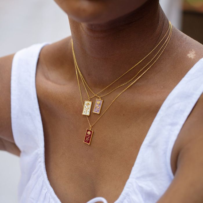 A model wearing three birth flower pendants stacked together.