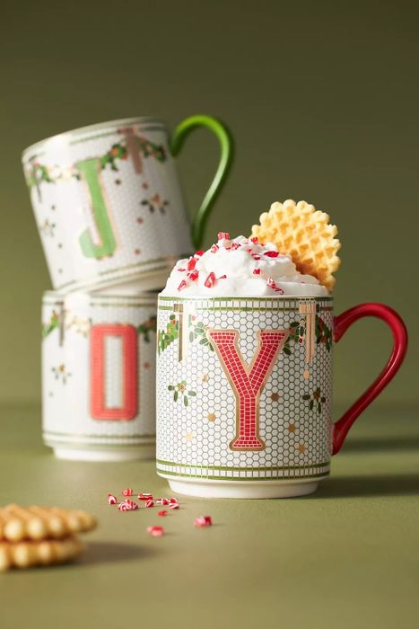 A festive tiled mug adorned with holly and a red initial.