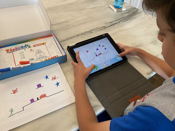 a child playing the video game they created using Pixicade on their tablet