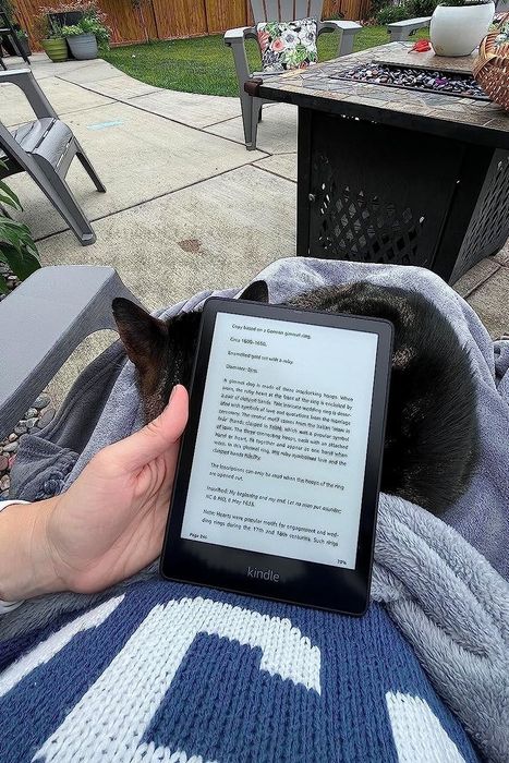 A reviewer enjoying their Kindle outside, soaking up the sunshine.
