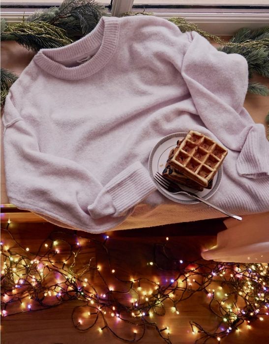 A cozy lavender sweater adorned with Christmas lights, perfect for the season.