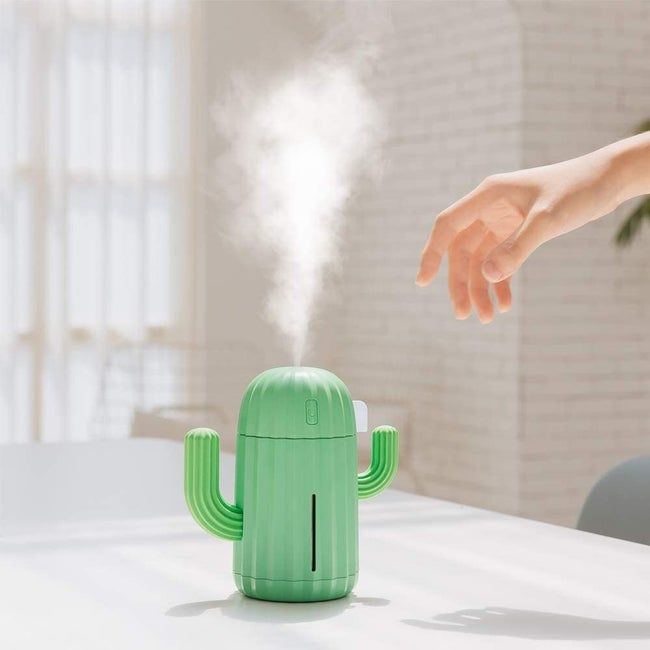 A green, cactus-shaped humidifier with two arms and steam coming out, looking like the cutest little plant buddy.
