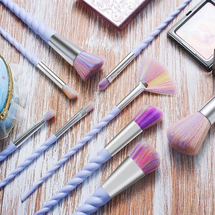 A set of makeup brushes with handles that are designed to resemble unicorn horns, featuring a mystical purple hue.