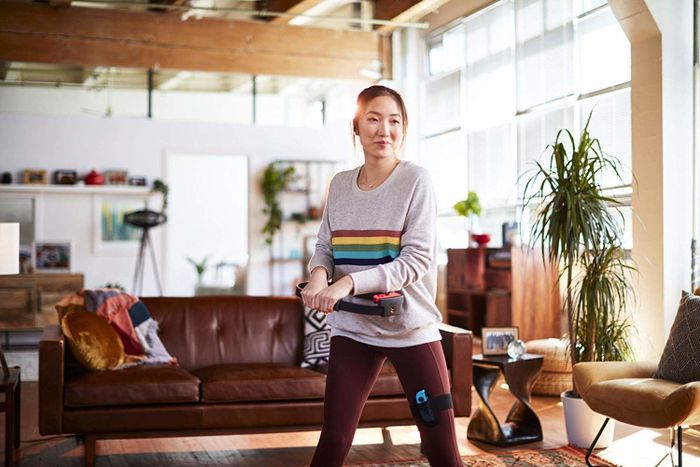A woman enjoys her workout session with Ring Fit in the comfort of her living room, fully engaged in the experience.