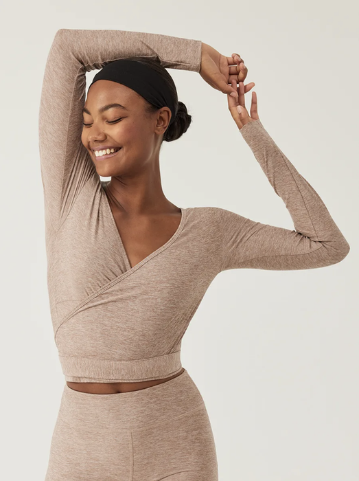 A model wears a light brown long-sleeve cropped wrap top with a V-neck, paired with matching bottoms, set against a white background.