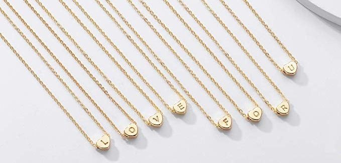 An array of thin gold necklaces, each with a gold heart featuring a personalized initial.