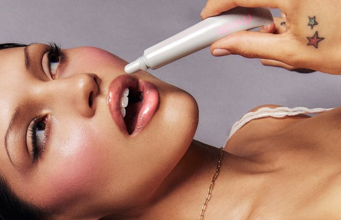 A model applying a lip treatment from a tube.