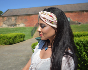A reviewer styling a tan headband with a knot in the center, adorned with delicate floral patterns, adding a vintage touch to their look.