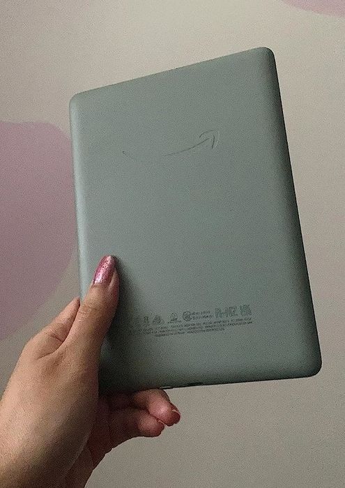 A hand holding a stylish agave green Kindle, ready for reading anywhere.