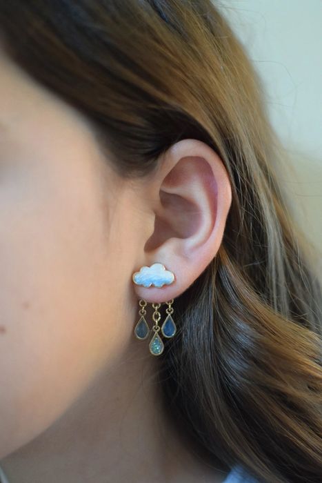 Someone wearing earrings featuring a cloud and raindrop design, effortlessly stylish.