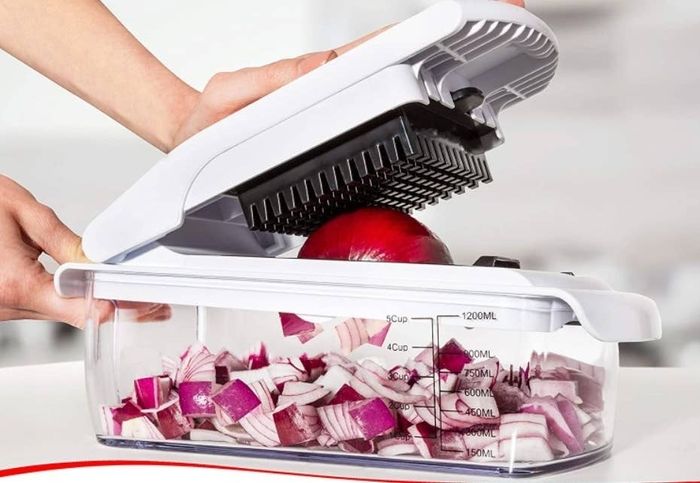 A model using the chopper to press down and easily cut through an onion.
