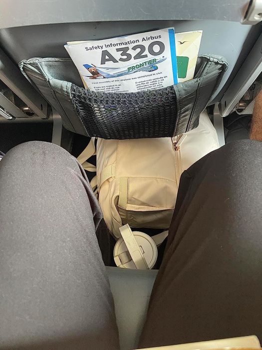 Reviewer’s beige bag tucked under an airplane seat.