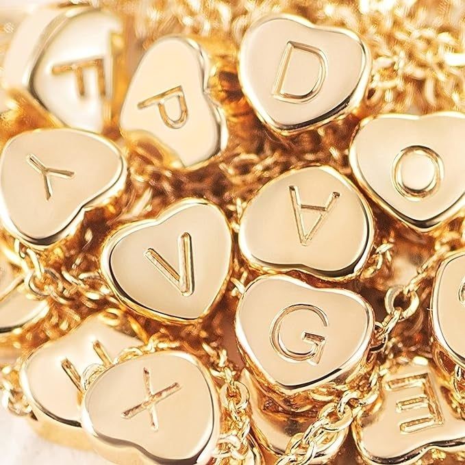 A collection of gold heart-shaped charms, each engraved with different initials.