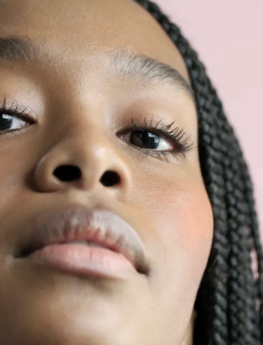 A model sporting a full makeup look using all three of the Glossier products in the trio.