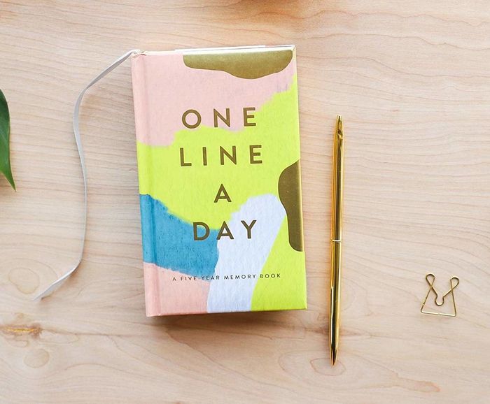 A One Line A Day journal with a cover painted in soft shades of pink, yellow, blue, and gold.
