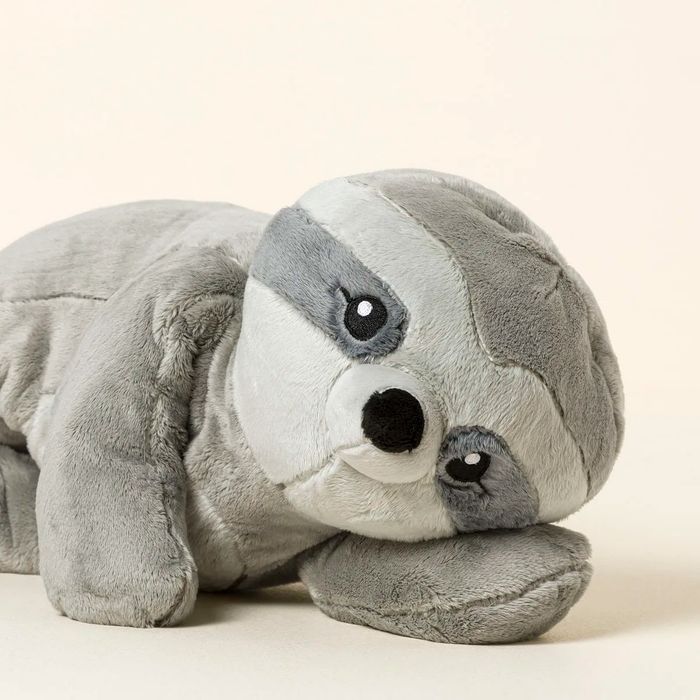 A plush sloth toy lying down, its head resting on its paw, wearing a content expression.
