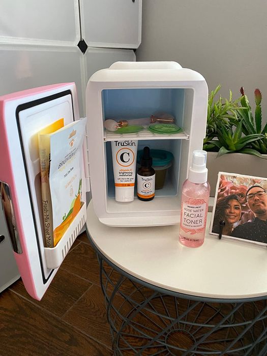 A reviewer's pink beauty fridge filled with various skincare products.