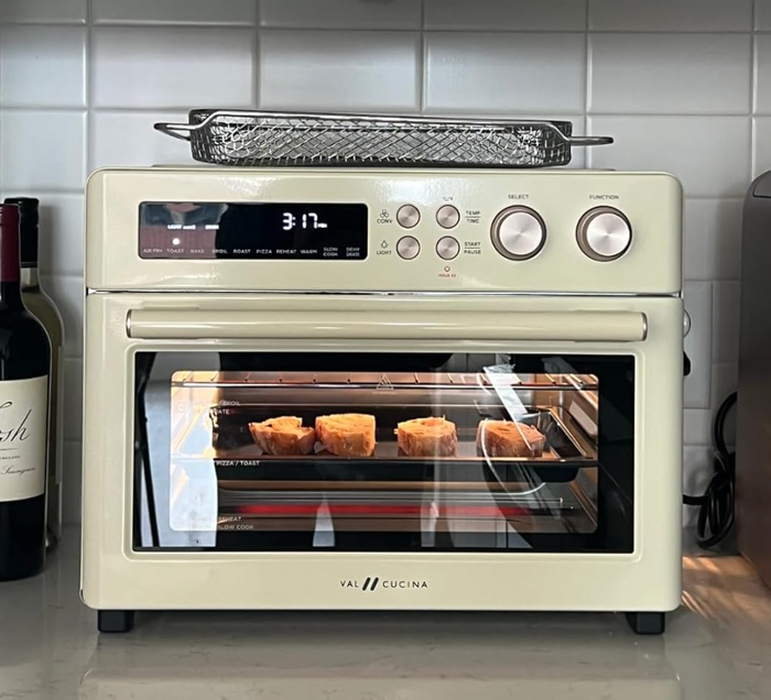 A white rectangular air fryer with a clear window, showing bread toasting inside.