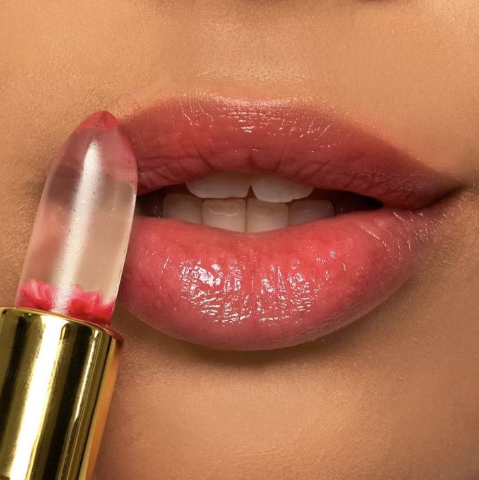 A glossy pink-lipped model applying the lipstick.