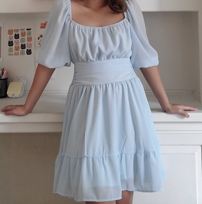 A reviewer wearing the blue dress, cinched at the waist with a belt.