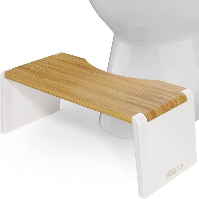 A white Squatty Potty placed in front of a toilet.