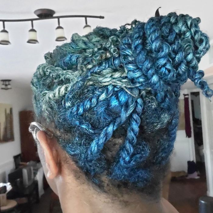 A reviewer showing off their hair after applying blue hair wax.