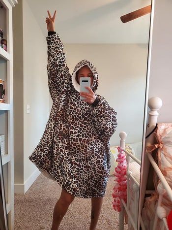 A reviewer models a leopard print hooded blanket
