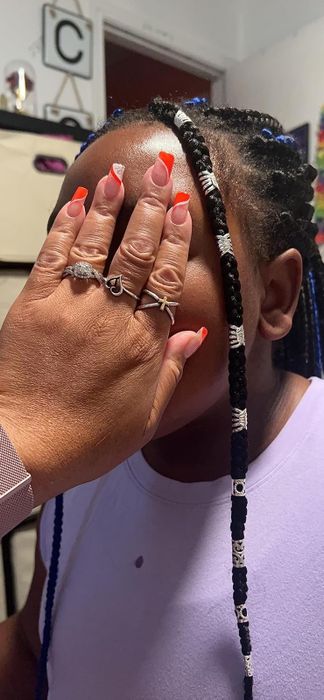 A reviewer proudly showing off their child's braids adorned with silver beads.