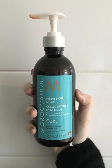 Hand holding a bottle of Moroccan oil