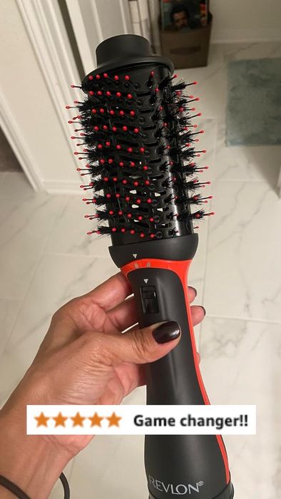 A close-up of a hand holding a Revlon hair dryer brush with a five-star review and the accompanying text
